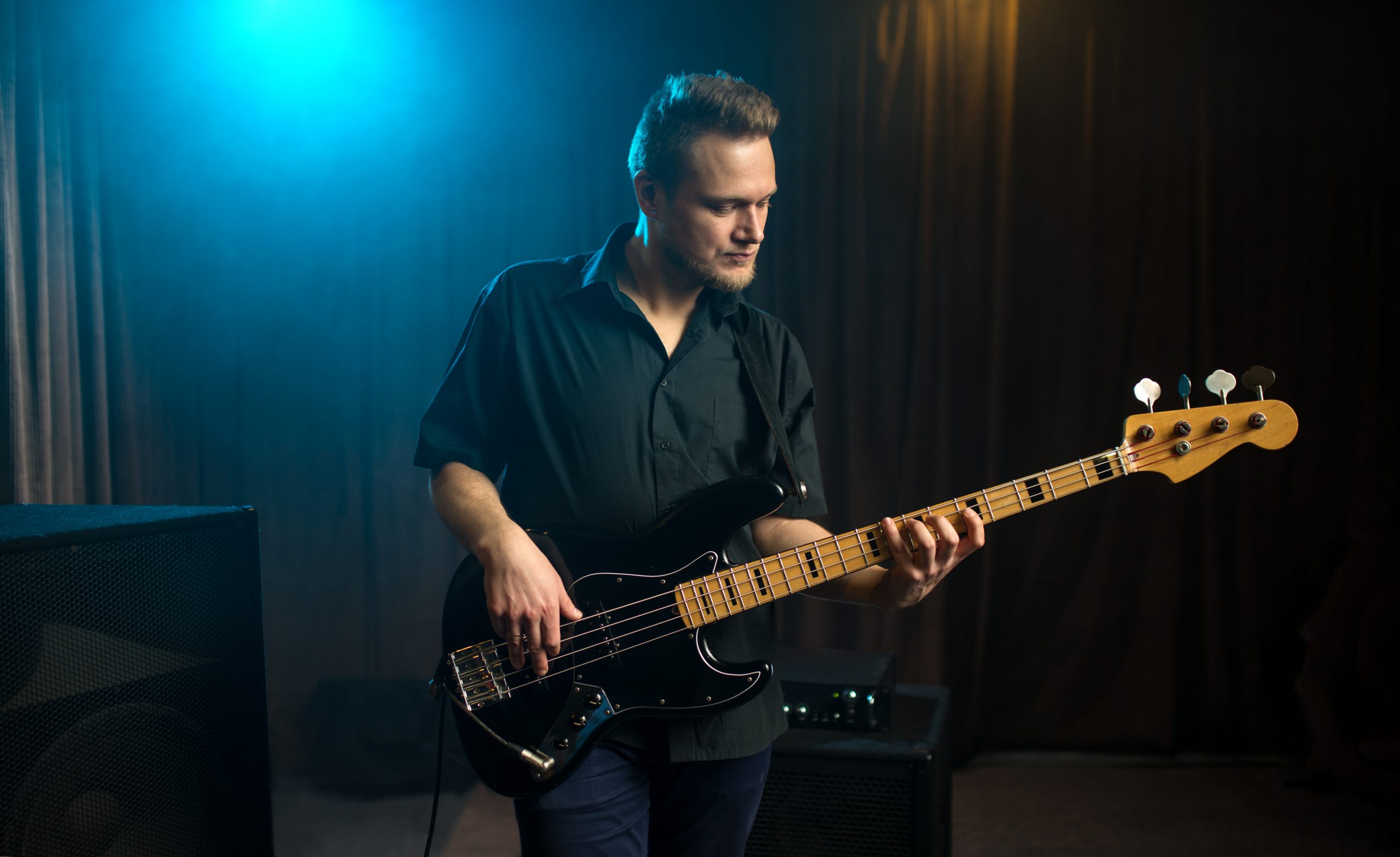 man playing bass guitar with blue light