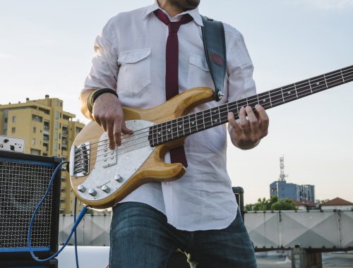 man holding bass guitar with amp plugged in behind