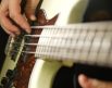finger strumming a bass guitar string