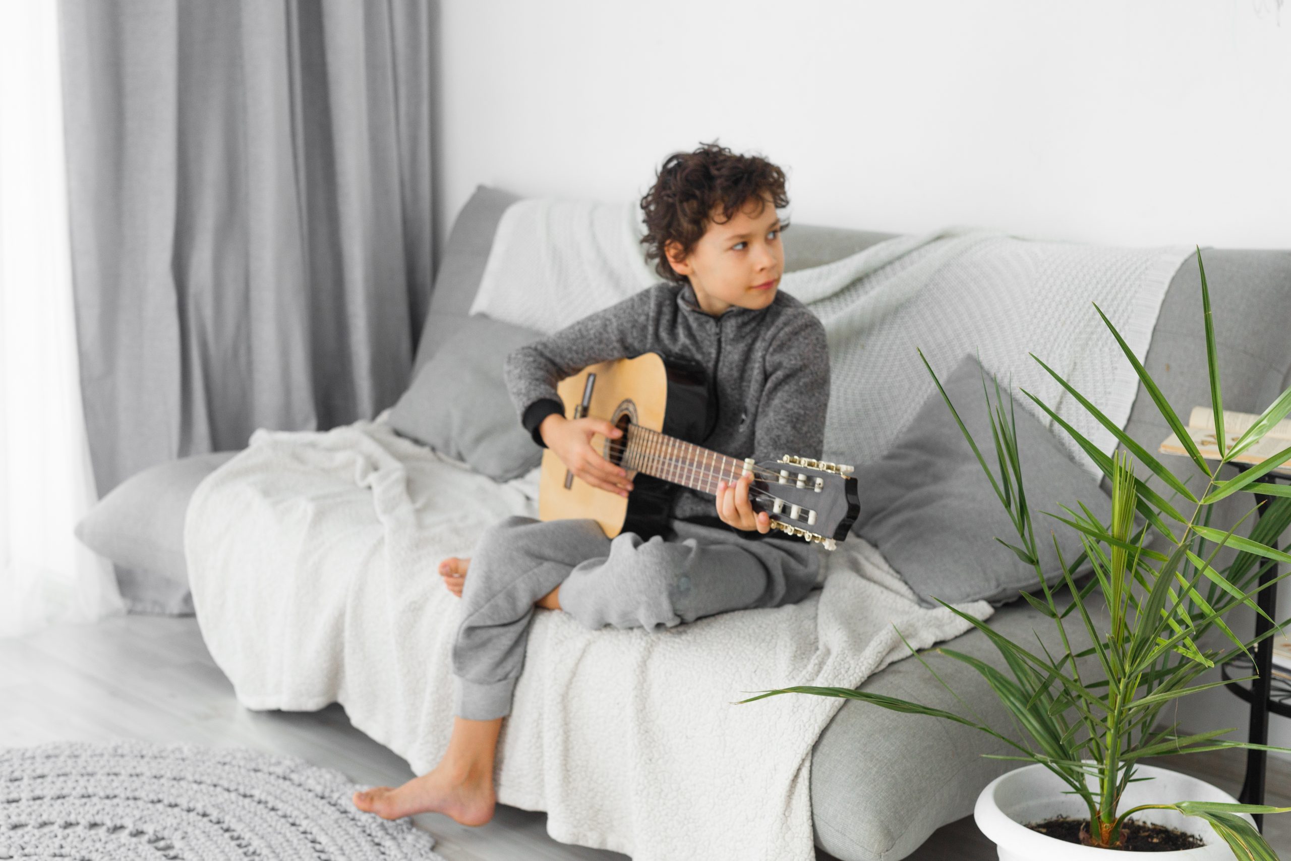 boy on couch for How Hard is it to Learn Guitar