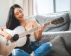 woman smiling holding instrument on couch for what makes a good guitar