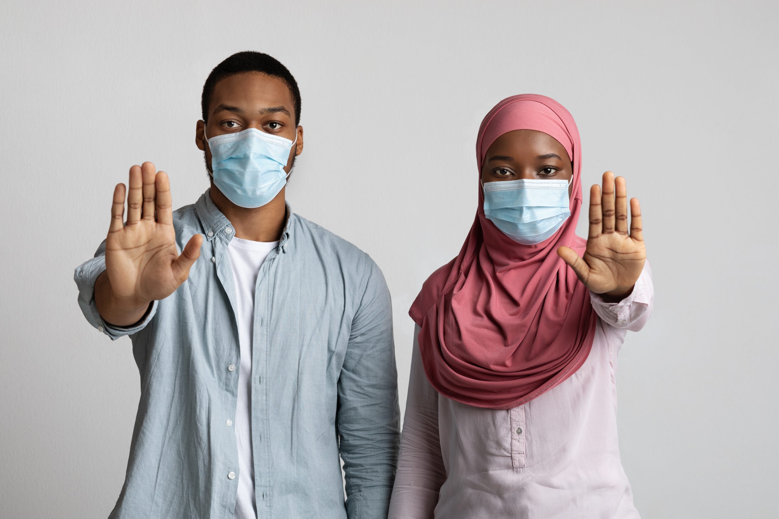 Music cancellations shown by Couple with masks, holding hands up to stop