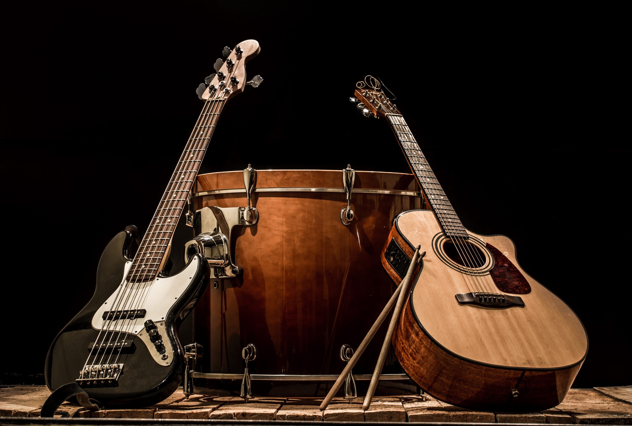 Guitar vs Bass photograph with both separate instruments leaned against drum