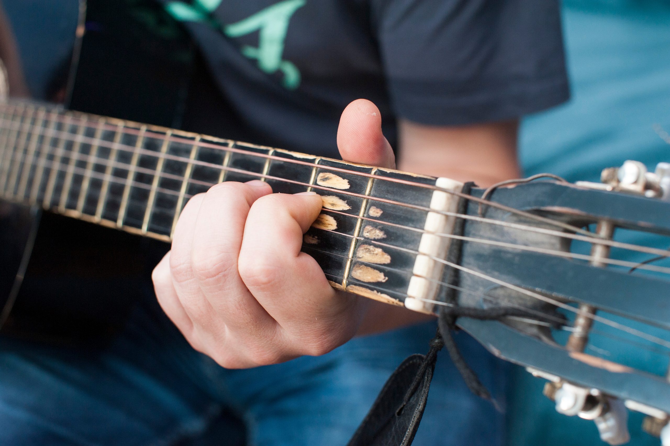 hand holding neck of guitar showing How Often Should You Change Guitar Strings