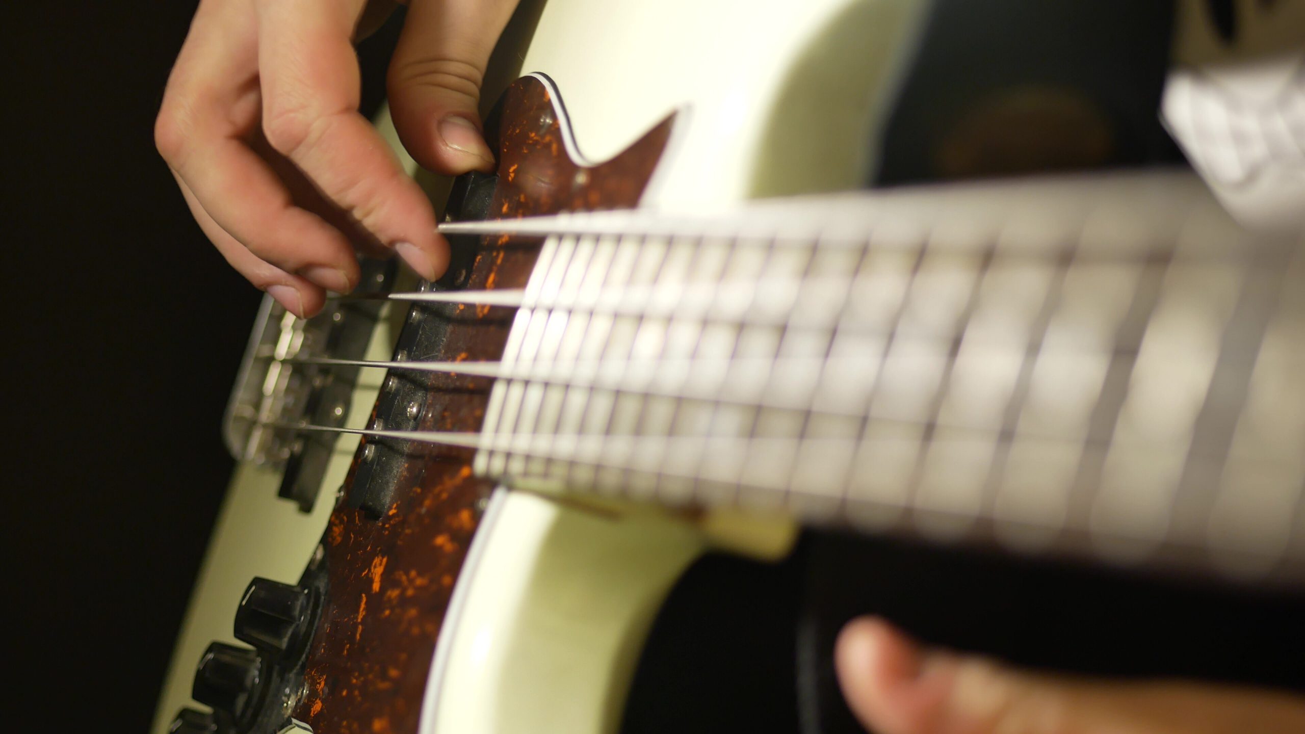 finger strumming a bass guitar string