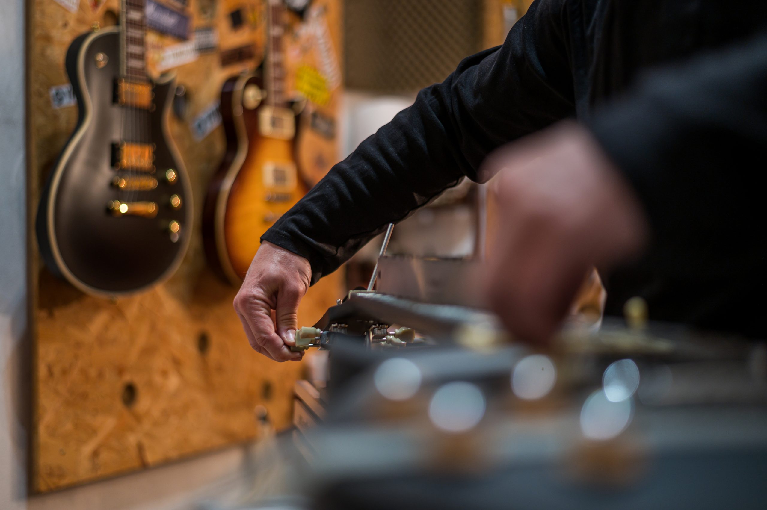 person adjusting a guitar on table