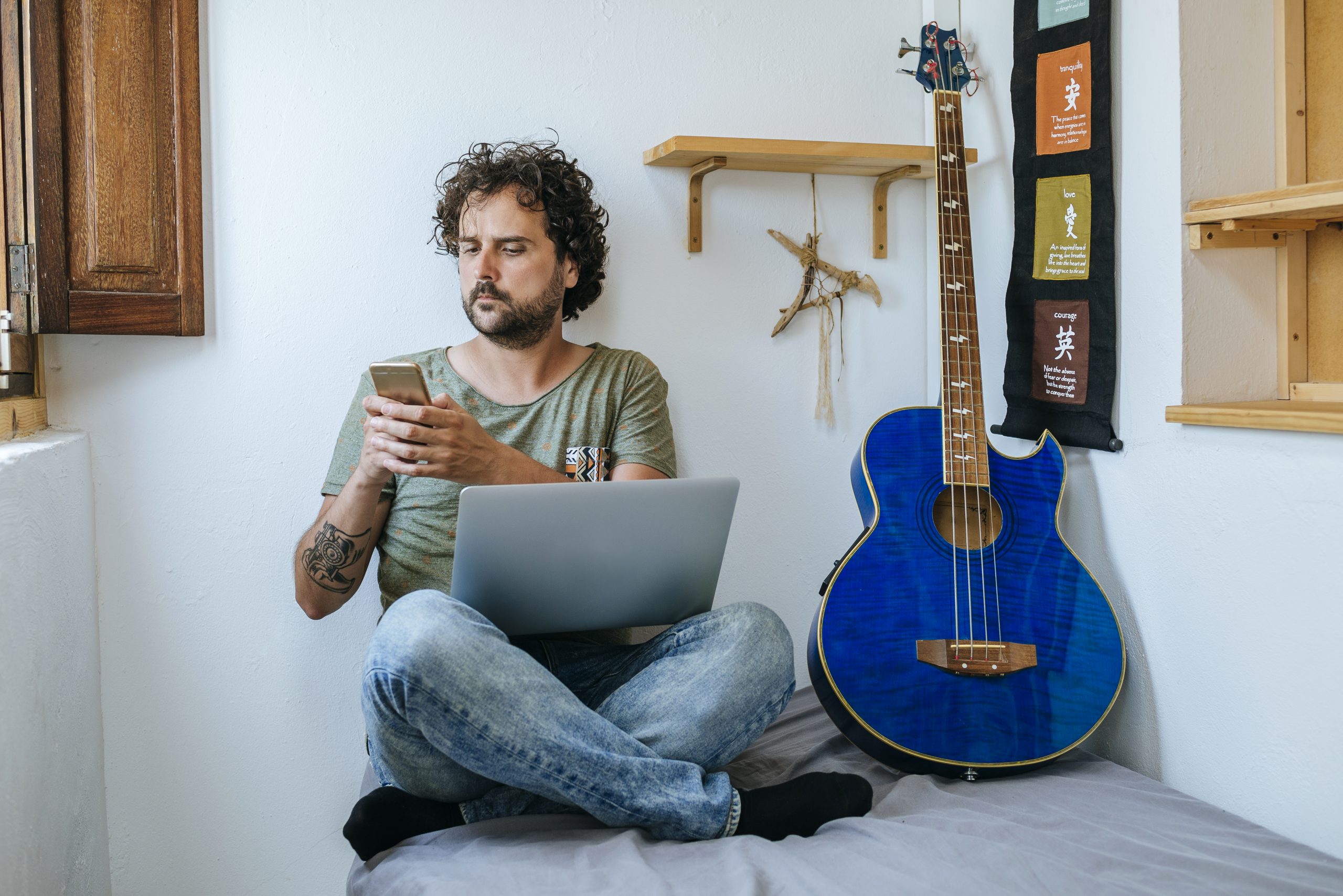 guy on computer with bass guitar next to him