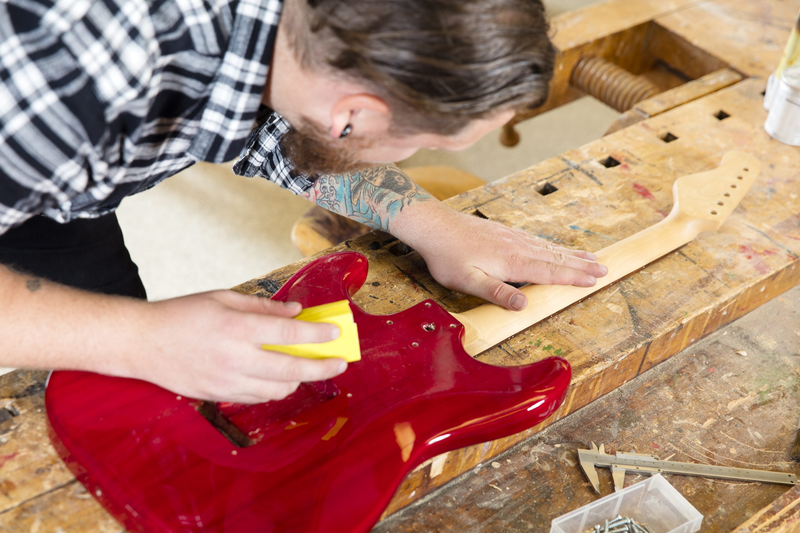 man painting a bass guitar in workshop