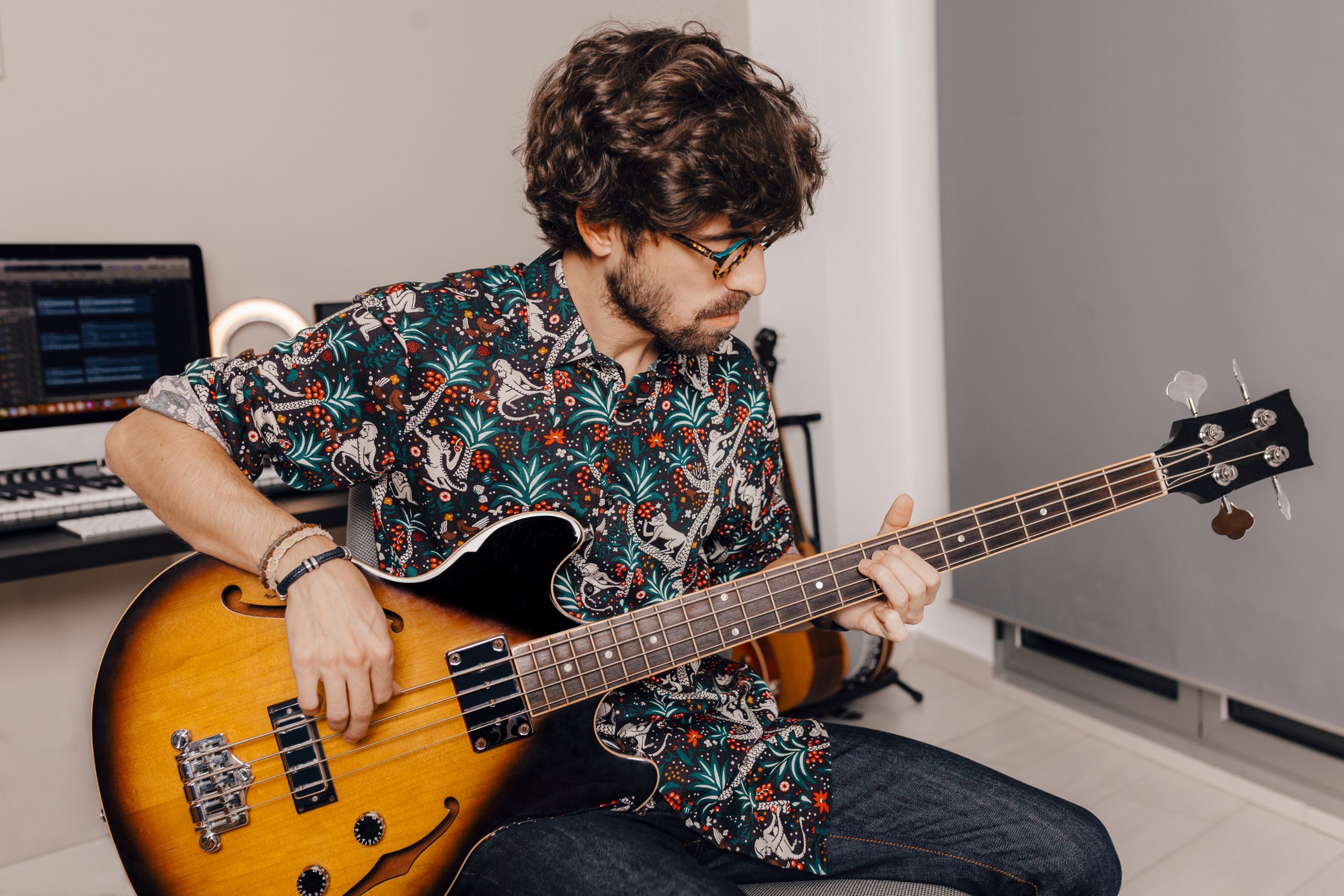 Male seated holding bass guitar for what is bass guitar used for