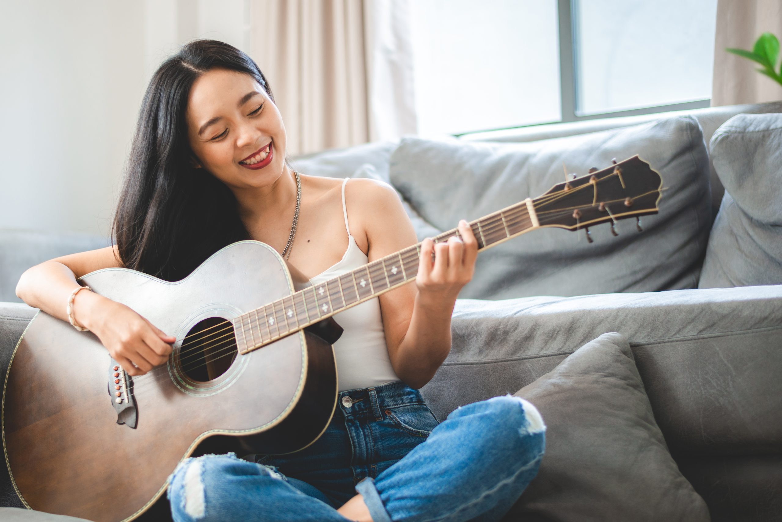 woman smiling holding instrument on couch for what makes a good guitar