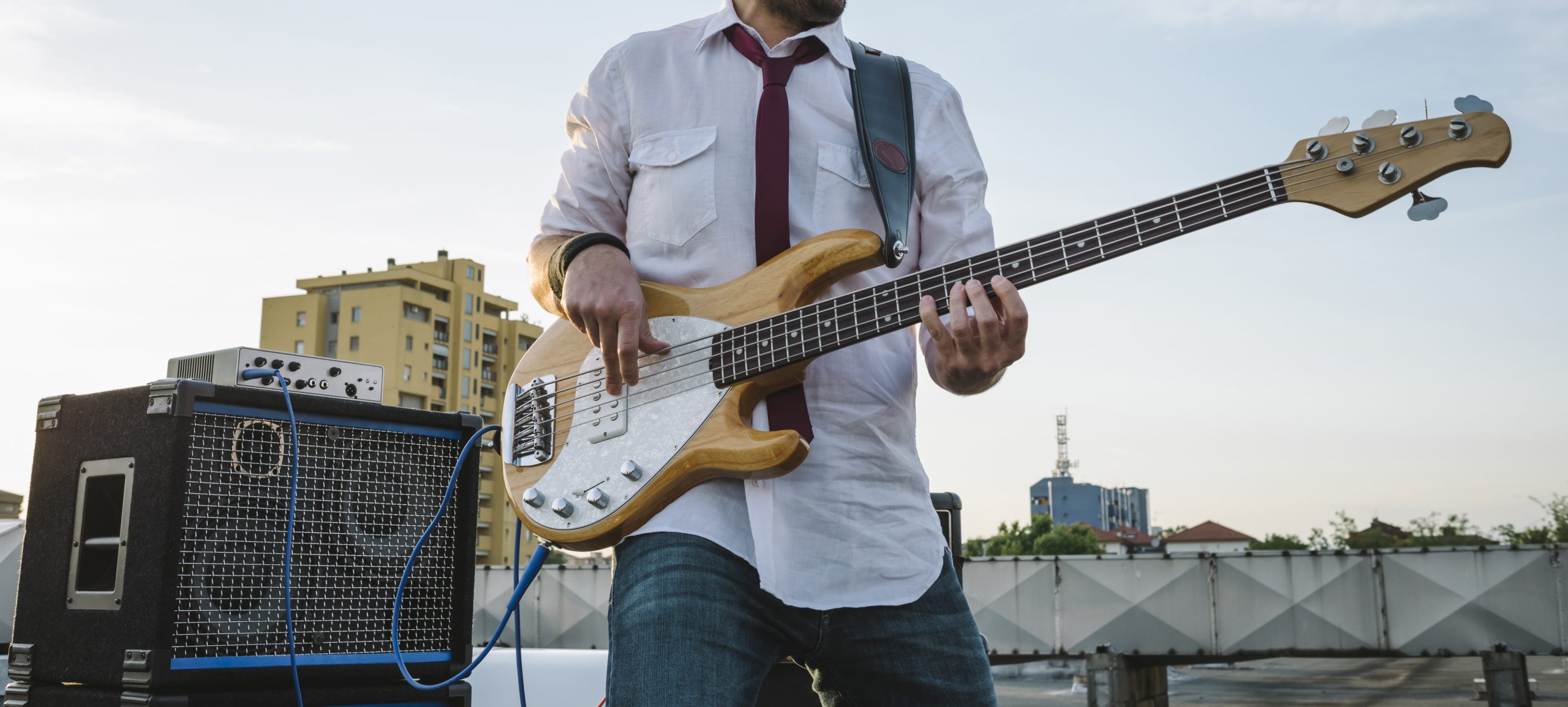 man holding bass guitar with amp plugged in behind